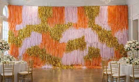 Decorative wall with orange and gold streamers in a formal event setting.